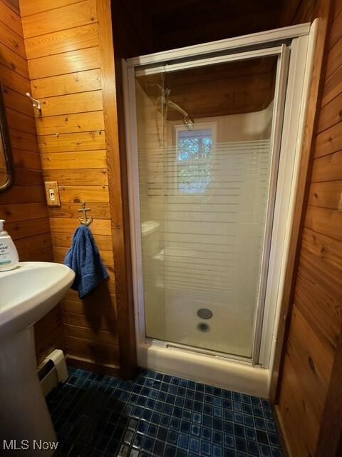 bathroom featuring wooden walls and a shower with door