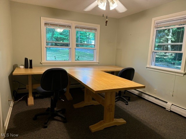 carpeted office space featuring ceiling fan, a healthy amount of sunlight, and baseboard heating