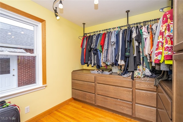 walk in closet with light hardwood / wood-style flooring