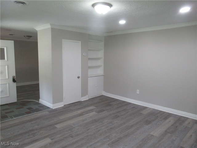 empty room featuring dark hardwood / wood-style floors, a textured ceiling, and built in shelves