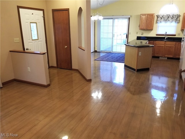 kitchen featuring hanging light fixtures, lofted ceiling, a notable chandelier, a center island, and dark hardwood / wood-style flooring