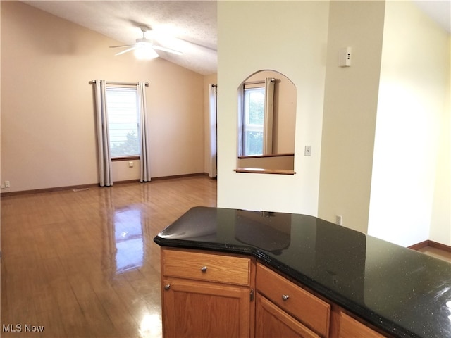 kitchen featuring light hardwood / wood-style flooring, a textured ceiling, ceiling fan, and vaulted ceiling