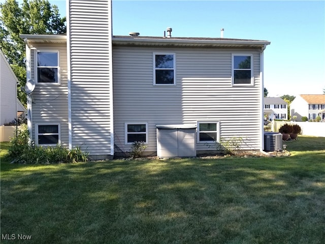 back of property with central air condition unit and a lawn