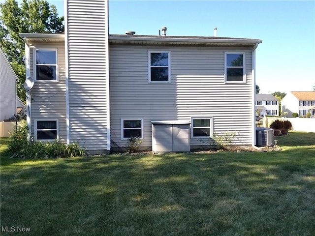 rear view of property featuring a chimney, a yard, and cooling unit