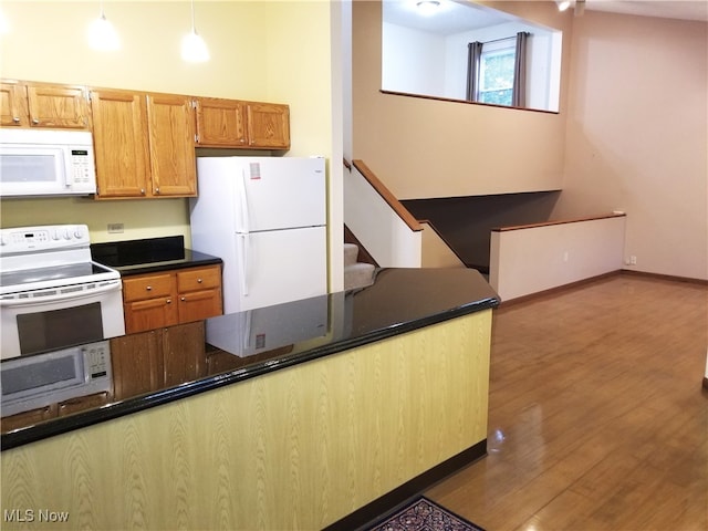 kitchen featuring pendant lighting, kitchen peninsula, dark hardwood / wood-style flooring, and white appliances