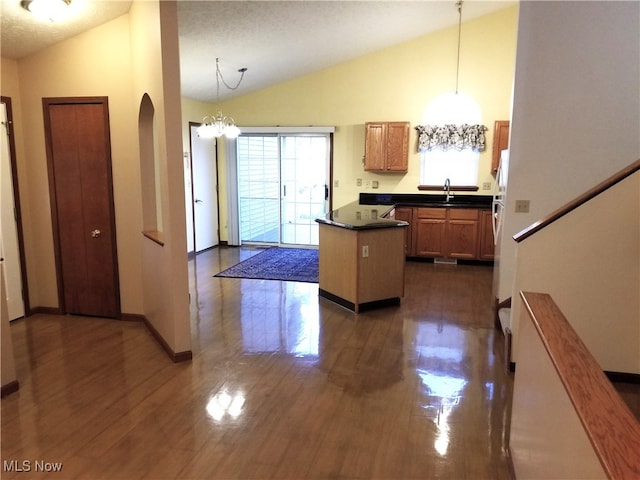 kitchen with hanging light fixtures, dark wood-type flooring, sink, and vaulted ceiling