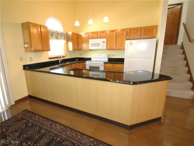 kitchen featuring a towering ceiling, dark hardwood / wood-style floors, pendant lighting, sink, and white appliances