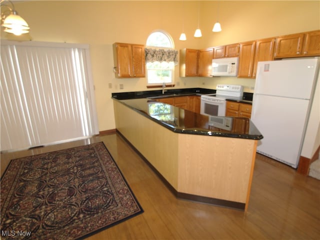 kitchen with pendant lighting, white appliances, sink, and light hardwood / wood-style floors