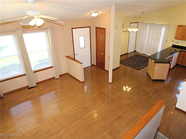 interior space with ceiling fan with notable chandelier, hardwood / wood-style flooring, and vaulted ceiling