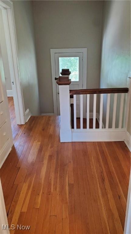 hall featuring light wood-type flooring and an upstairs landing