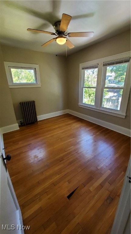 spare room with radiator, hardwood / wood-style flooring, and ceiling fan