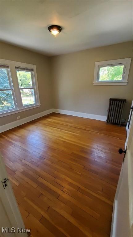 empty room with wood-type flooring and radiator