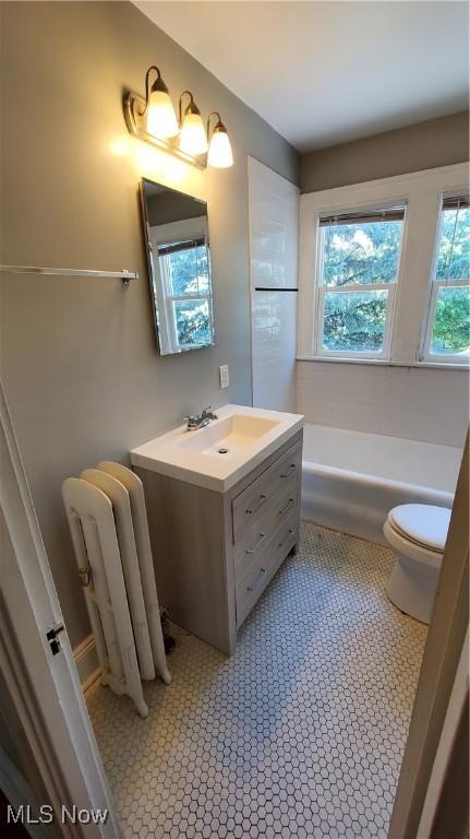 bathroom featuring radiator, toilet, vanity, and tile patterned flooring