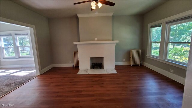 unfurnished living room featuring ceiling fan, dark hardwood / wood-style floors, and radiator heating unit