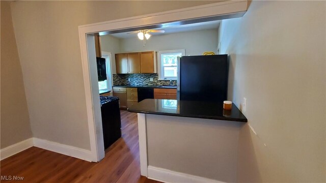 kitchen featuring light brown cabinetry, black appliances, dark hardwood / wood-style floors, ceiling fan, and decorative backsplash