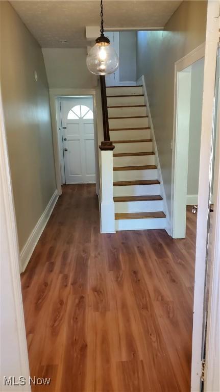 stairs featuring a textured ceiling and hardwood / wood-style flooring