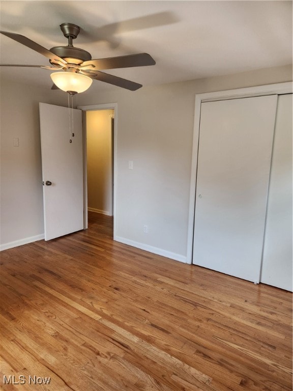 unfurnished bedroom featuring light wood-style floors, a closet, ceiling fan, and baseboards