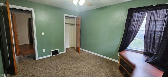 unfurnished bedroom featuring baseboards, visible vents, dark carpet, and a closet