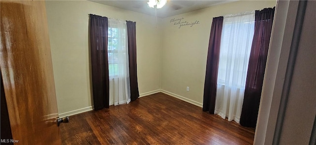 empty room featuring dark wood-style floors, baseboards, and a ceiling fan