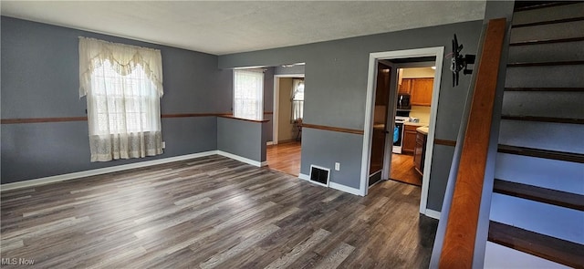 unfurnished room with visible vents, dark wood finished floors, and baseboards