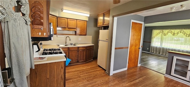 kitchen with brown cabinets, light countertops, wood finished floors, and freestanding refrigerator