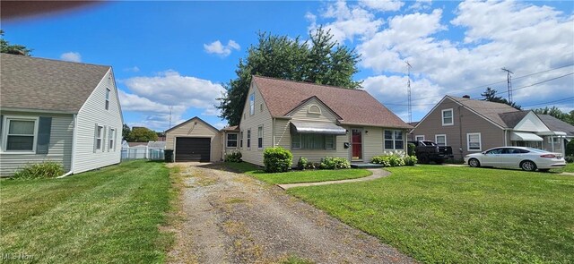 view of front facade with dirt driveway, an outbuilding, a detached garage, and a front yard