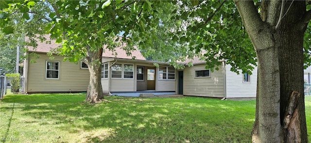 rear view of house with a shingled roof, a yard, and fence