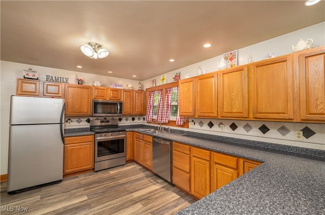 kitchen with hardwood / wood-style flooring, decorative backsplash, sink, and stainless steel appliances