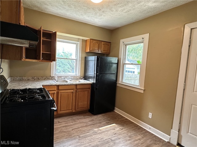 kitchen featuring black appliances, light hardwood / wood-style flooring, extractor fan, and a wealth of natural light