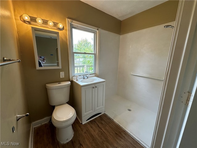 bathroom featuring vanity, a textured ceiling, hardwood / wood-style flooring, walk in shower, and toilet