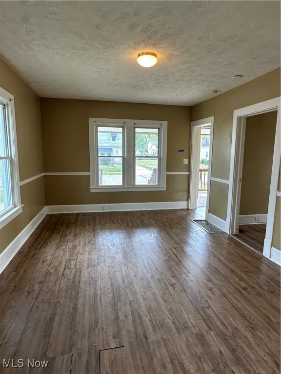 spare room with a textured ceiling and dark hardwood / wood-style flooring