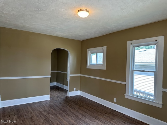 spare room featuring a textured ceiling and dark wood-type flooring