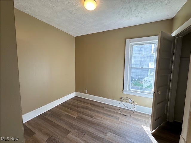 unfurnished bedroom featuring multiple windows, dark wood-type flooring, and a textured ceiling