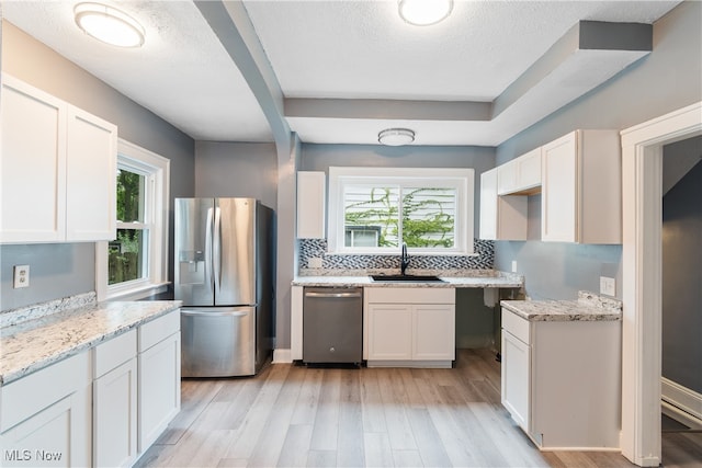 kitchen with white cabinets, appliances with stainless steel finishes, and a healthy amount of sunlight