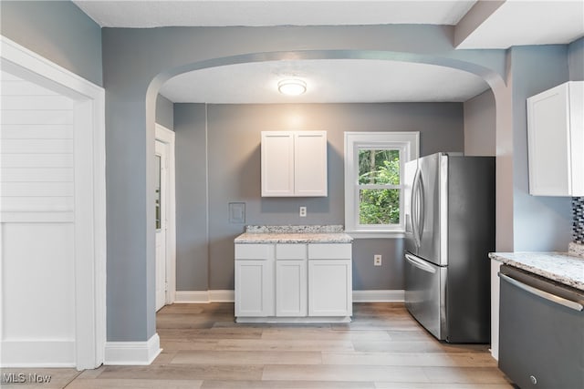 kitchen with light stone countertops, appliances with stainless steel finishes, light hardwood / wood-style flooring, and white cabinetry