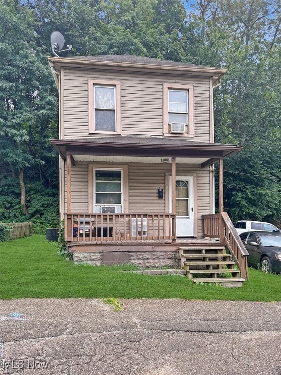 view of front of home featuring a front lawn, cooling unit, and covered porch