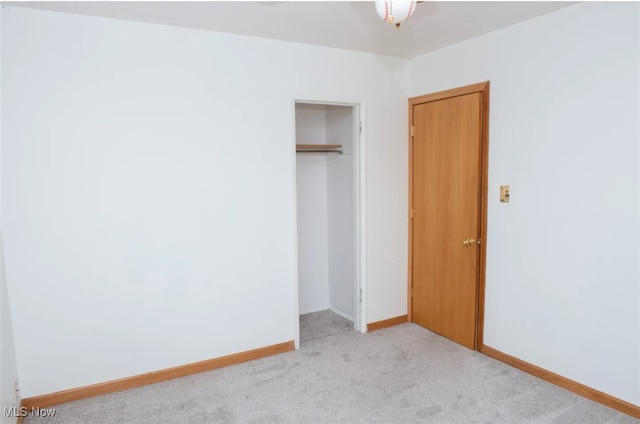 unfurnished bedroom featuring light colored carpet and a closet