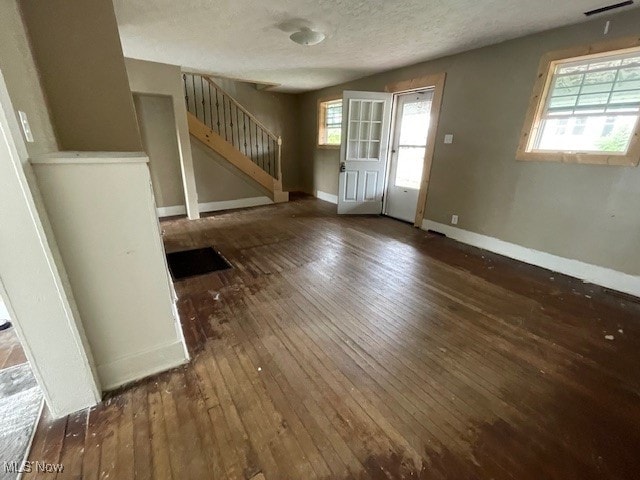 unfurnished living room featuring a wealth of natural light, wood-type flooring, and a textured ceiling