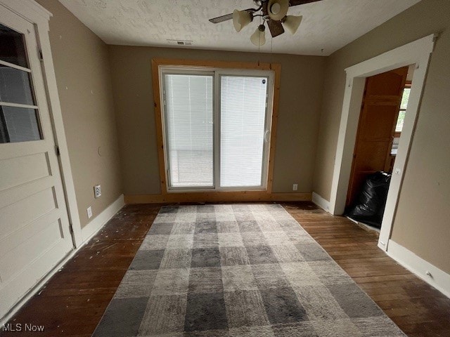 interior space featuring ceiling fan, plenty of natural light, a textured ceiling, and dark wood-type flooring