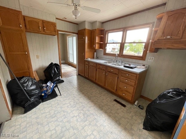 kitchen with sink, ceiling fan, light tile patterned floors, and crown molding