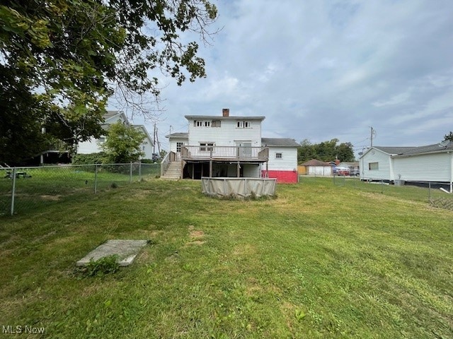 rear view of house featuring a deck and a yard