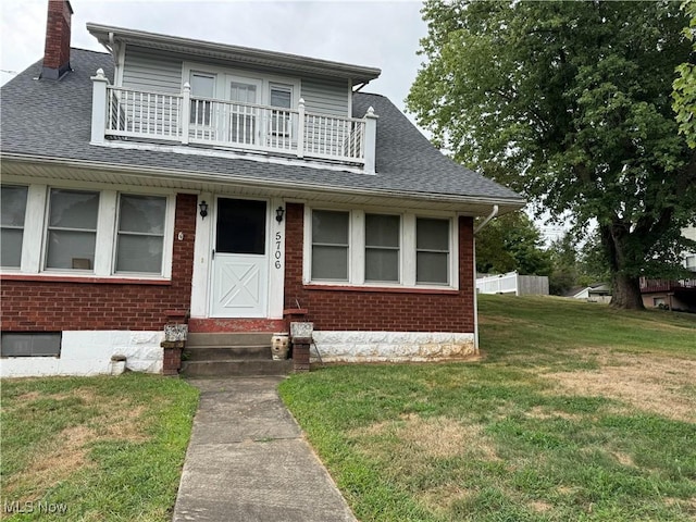 view of front of home featuring a balcony and a front yard