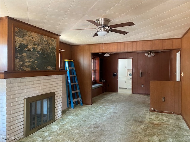 unfurnished living room with a fireplace, wooden walls, light colored carpet, and ceiling fan