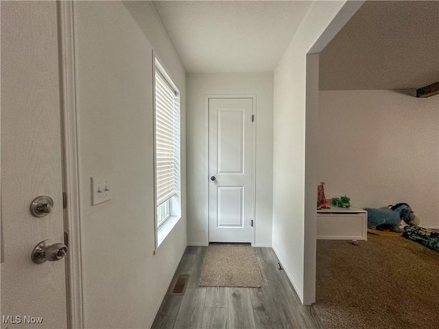 doorway with baseboards, wood finished floors, visible vents, and a healthy amount of sunlight