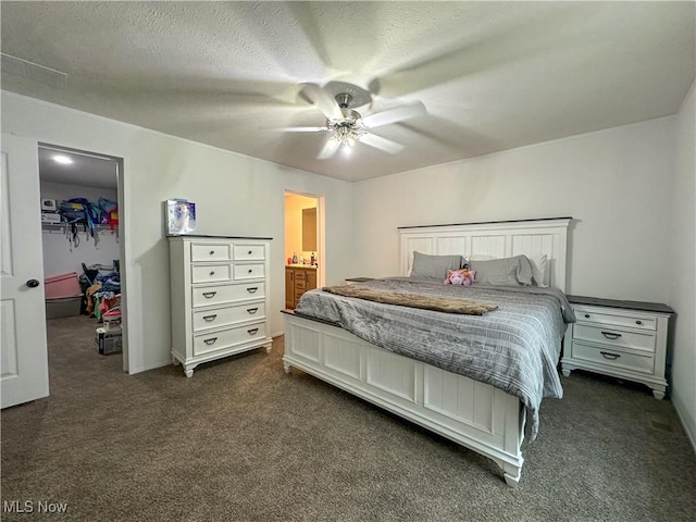 bedroom featuring a textured ceiling, ceiling fan, a spacious closet, a closet, and dark colored carpet