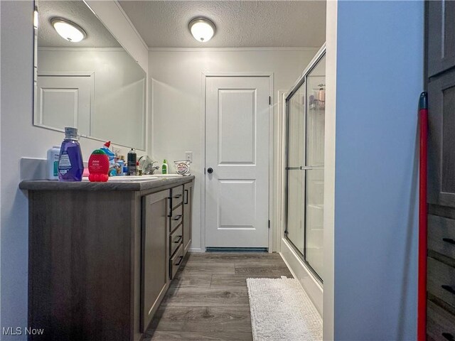 bathroom featuring a stall shower, a textured ceiling, vanity, and wood finished floors