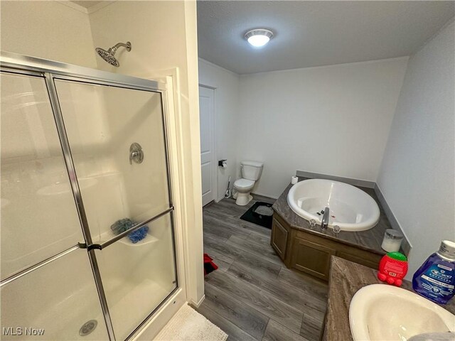 full bath with a bath, wood finished floors, a shower stall, and toilet