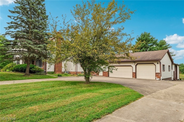 view of property hidden behind natural elements featuring a garage and a front lawn