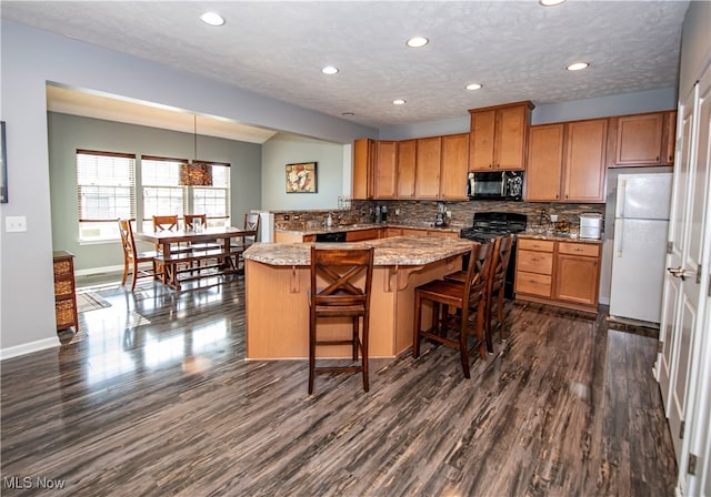 kitchen with hanging light fixtures, dark wood-type flooring, range, and white fridge