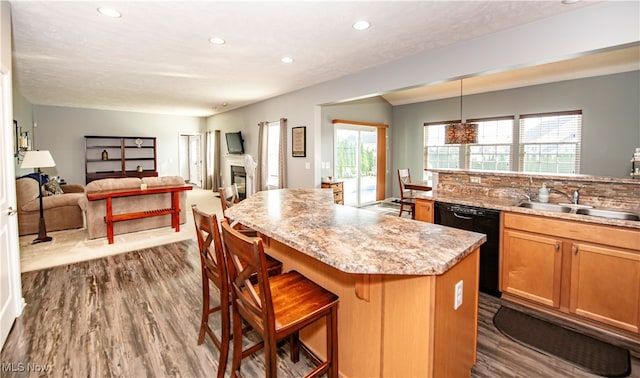 kitchen featuring dishwasher, a kitchen bar, dark hardwood / wood-style flooring, a kitchen island, and hanging light fixtures